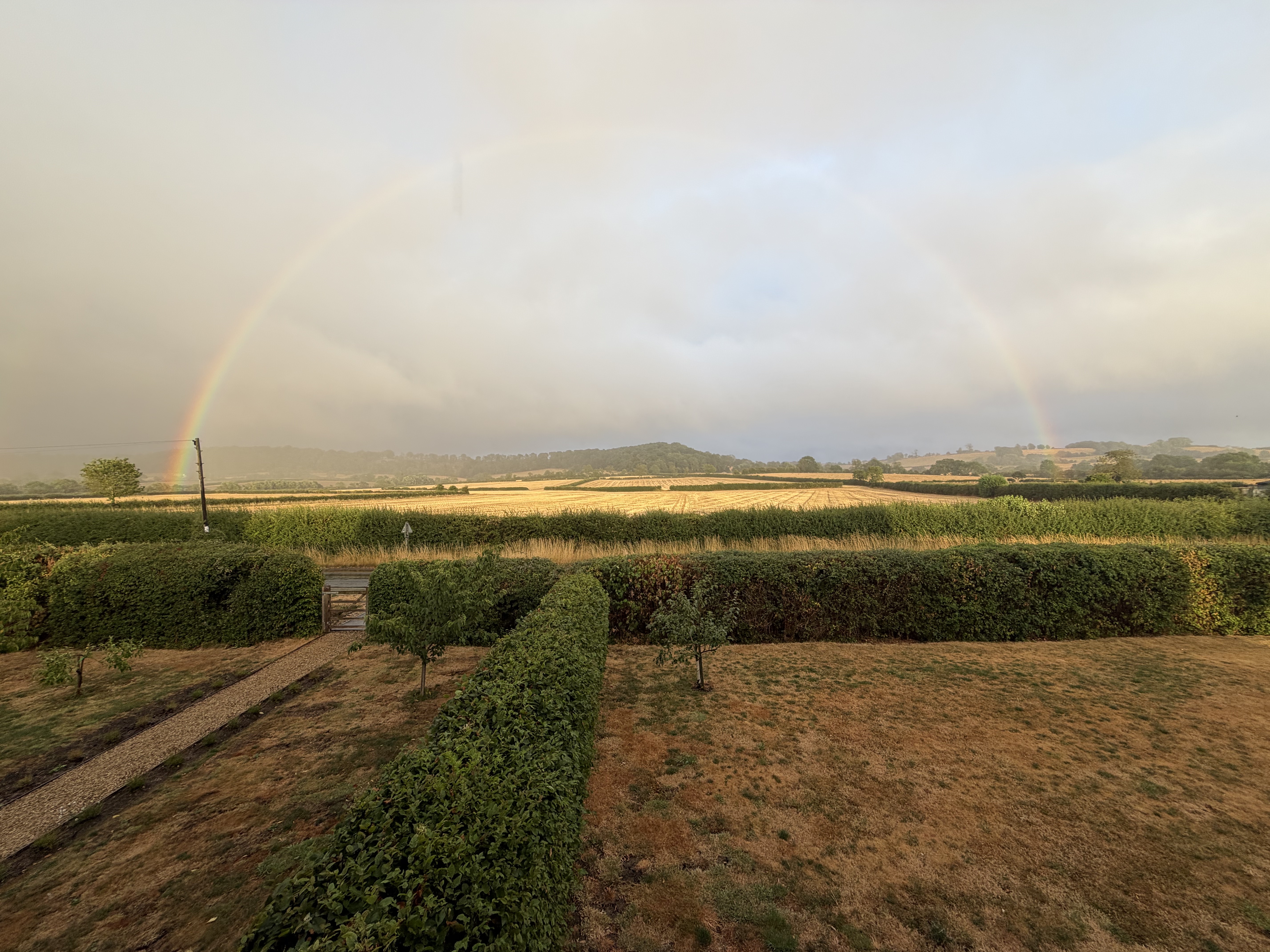 Hedges overlooking the South Warwickshire countryside beneath a rainbow